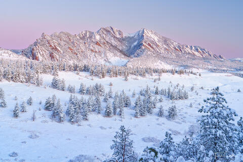 a photo of the boulder flatirons just before sunrise the morning after a snowstorm dropped several inches of snow on the region.