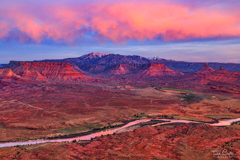 a photo overlooking castle valley near moab at sunset with the colorado river flowing below.