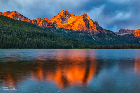 a photo of mcgown peak in the sawtooth range of idaho reflected in Stanley Lake at sunrise