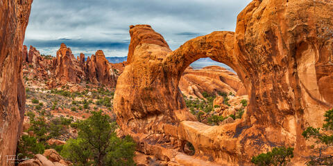 double-o arch frames sandstone fins in arches national park, utah, as seen in this panoramic image.