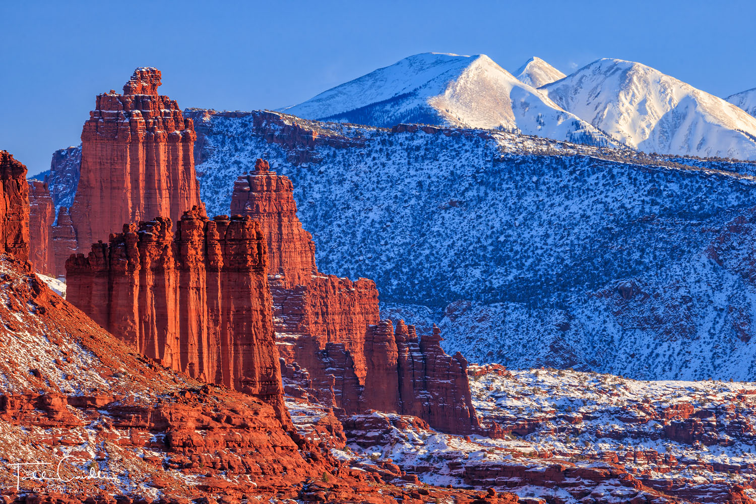 The incredible sandstone monoliths of Fisher Towers stand in stark contrast to the wintry alpine view of the La Sal Mountains...