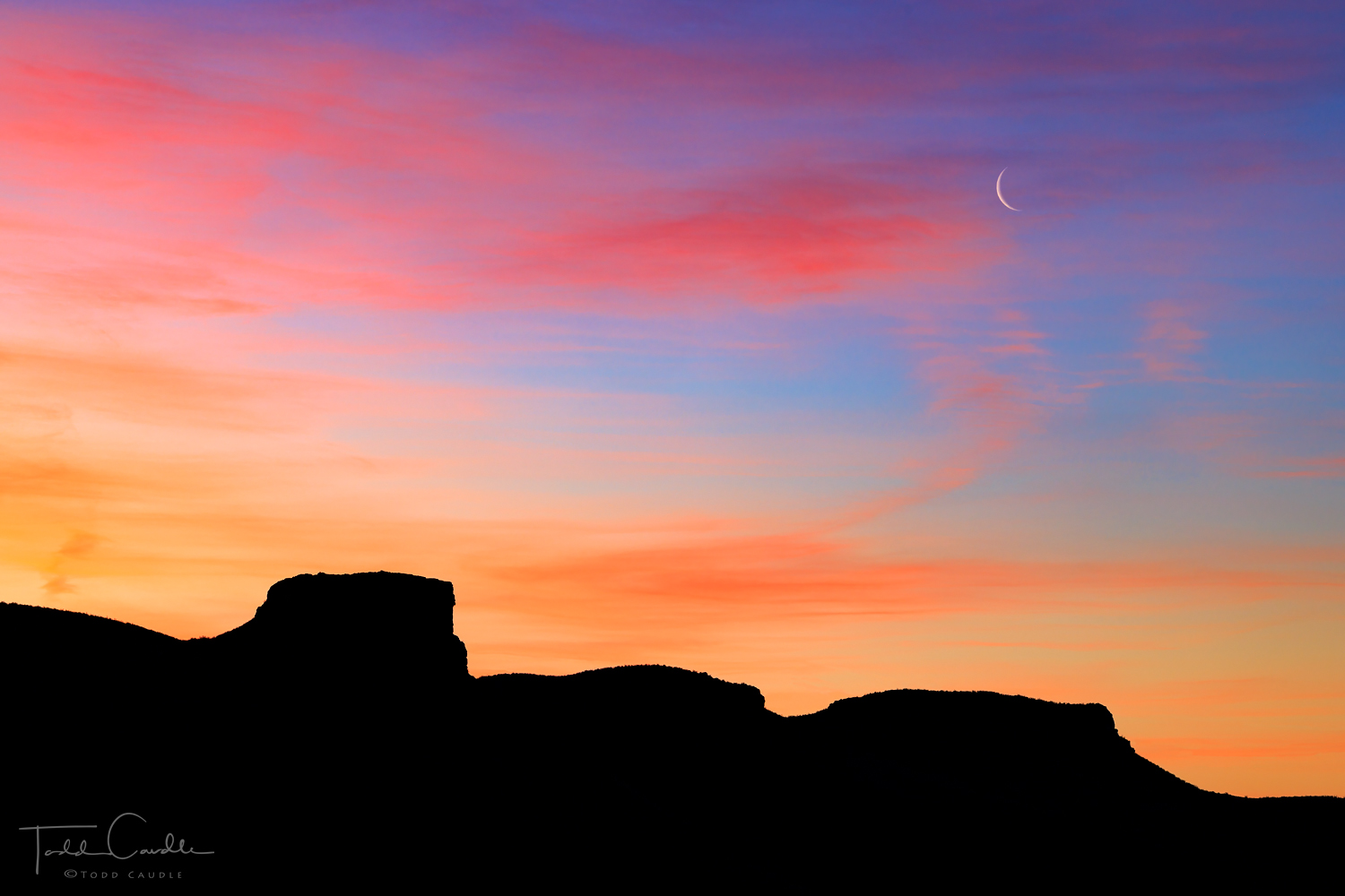 A crescent moon rises above South Table Mountain in Golden.