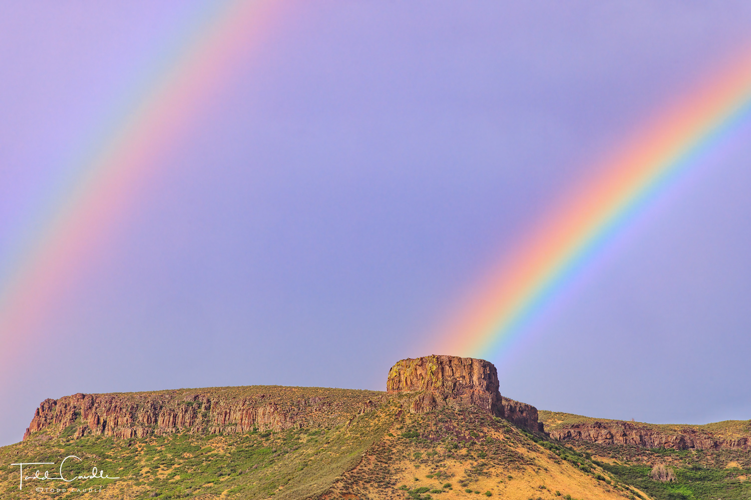 A double rainbow arcs over Castle Rock and South Table Mountain in Golden.