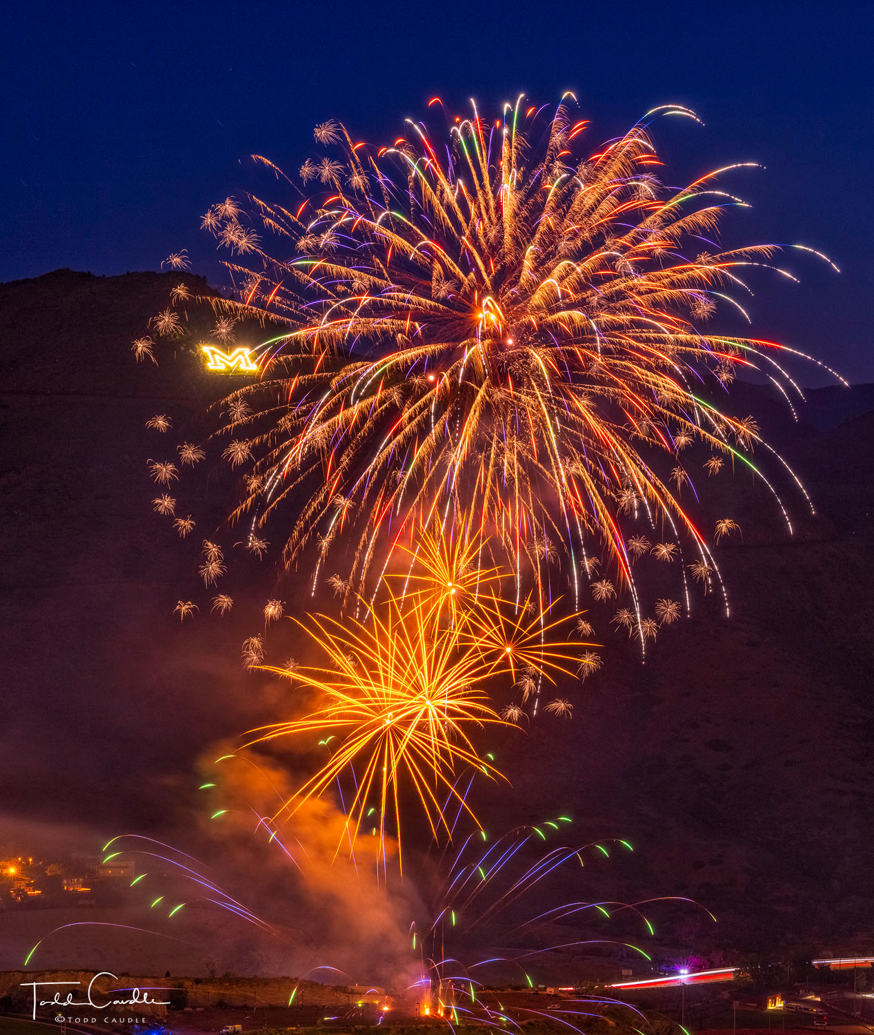 Fireworks burst in the air in front of Mount Zion and the Colorado School of Mines "M" logo.