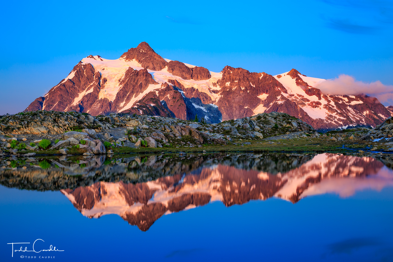 Mount Shuksan reflects alpenglow light in a small tarn at Artist's Point at sunset.