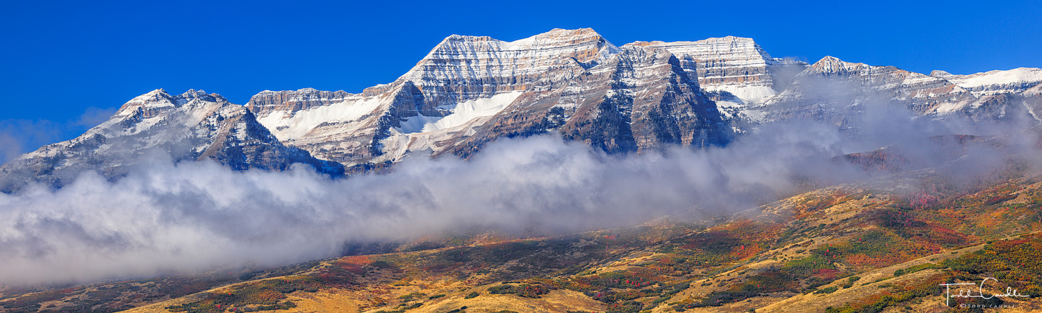 On an otherwise cloudless day, a cloudbank left over from early morning valley fog hugs the lower slopes of mighty Mount Timpanogos...
